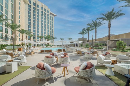 seating area outside with chairs and pool and palm trees.