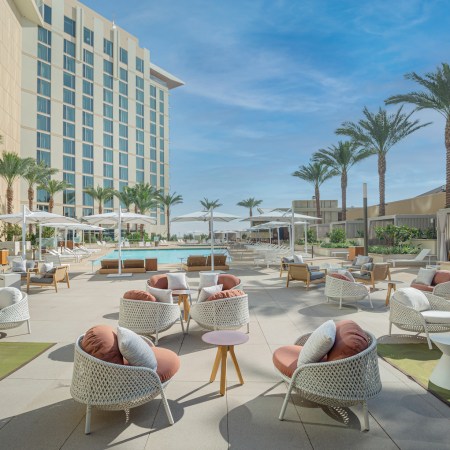 seating area outside with chairs and pool and palm trees.