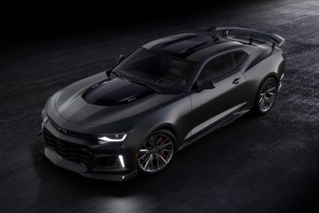 Black Chevrolet Camaro driving on black surface.