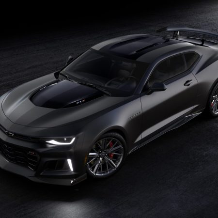 Black Chevrolet Camaro driving on black surface.