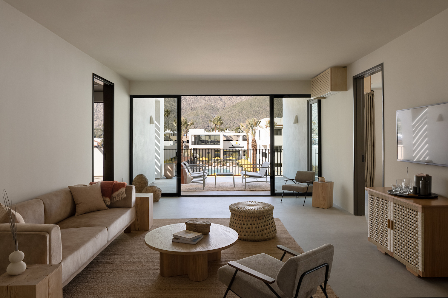 Tan-colored living room in a hotel with scenic balcony.