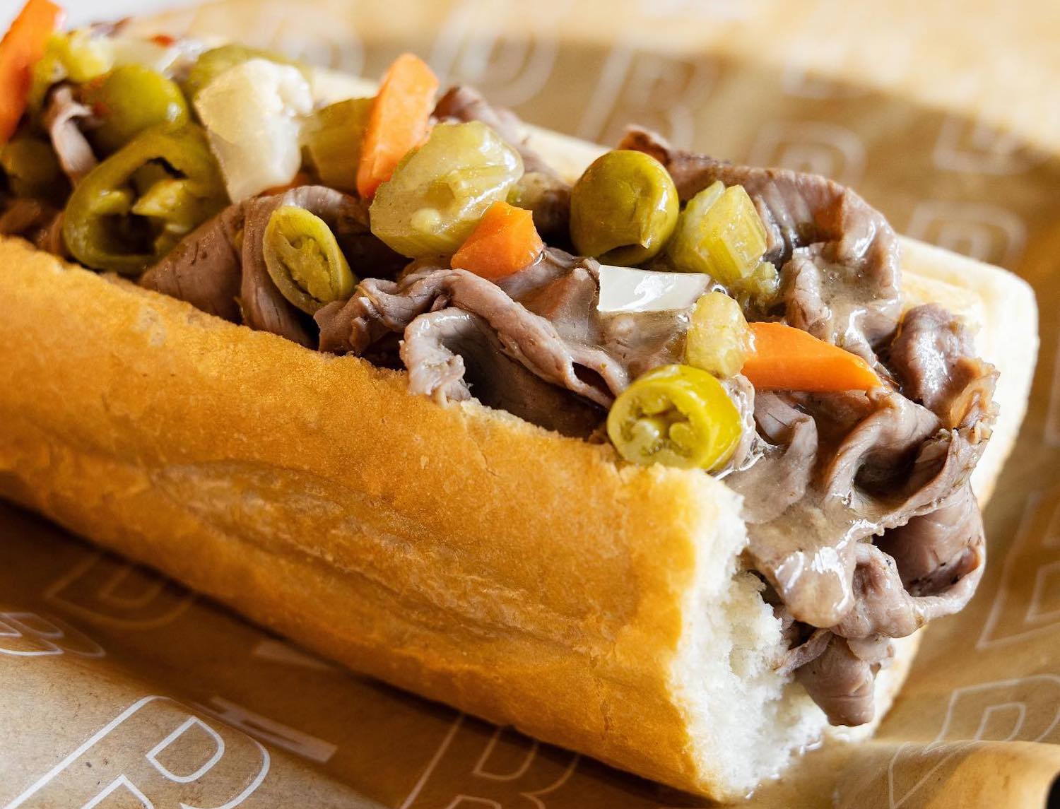 beef sandwich with banana peppers, onions and carrot on a roll