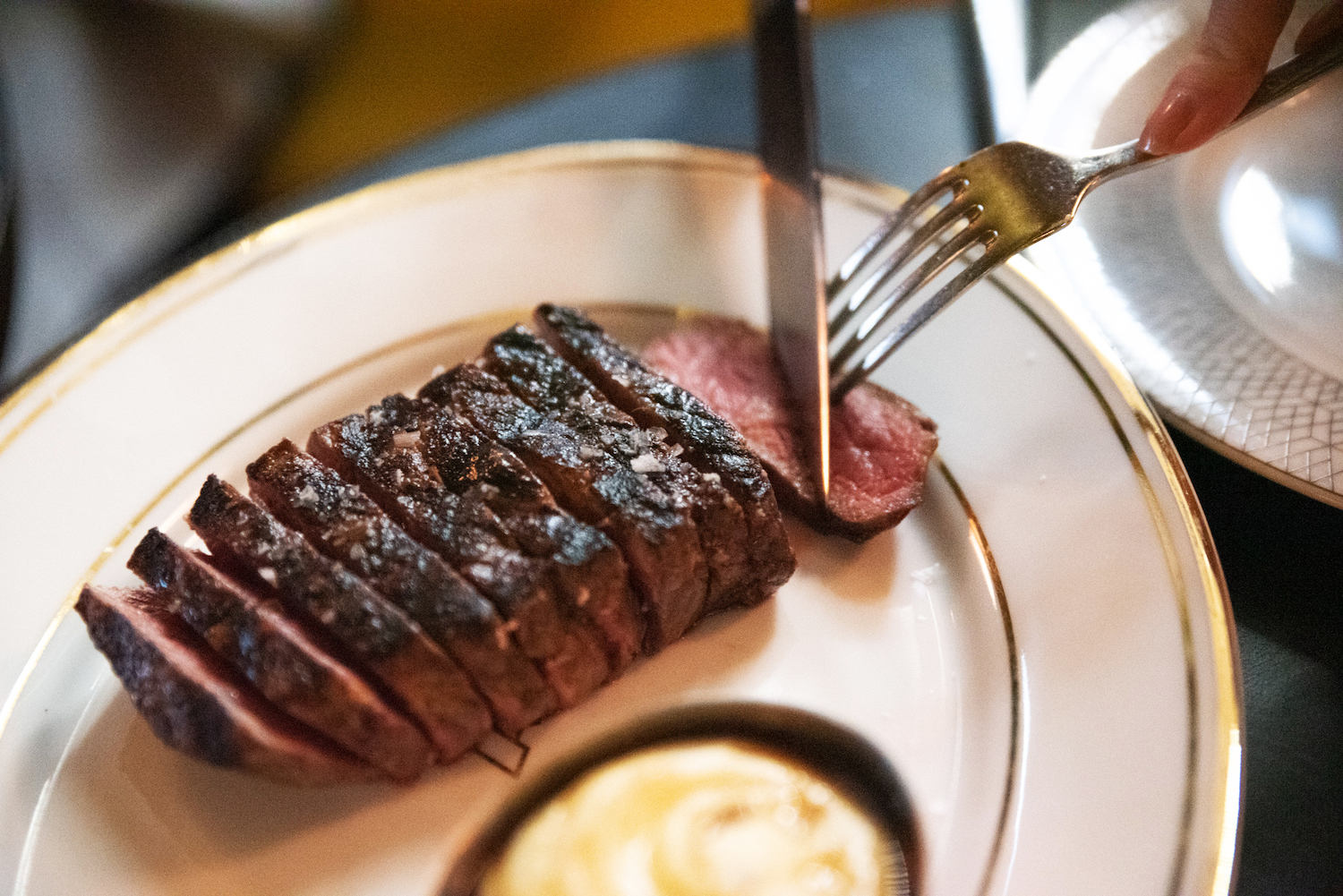 A sliced piece of wagyu steak being cut up on a plate.