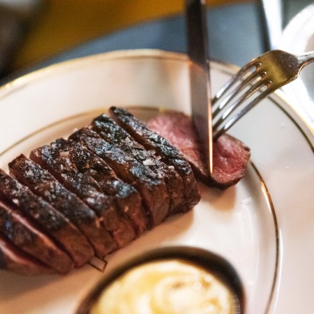 A sliced piece of wagyu steak being cut up on a plate.
