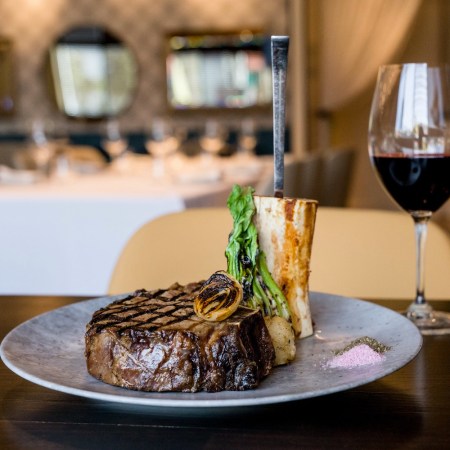 Plated steak next to a glass of red wine.