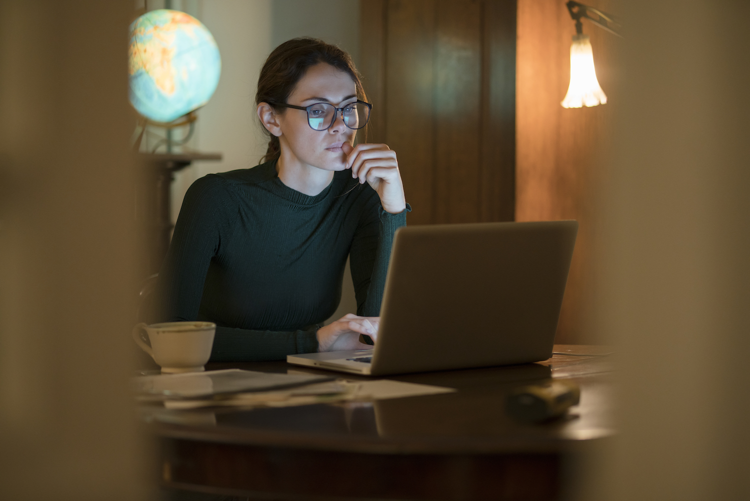 professional woman working in her home study at night with a laptop on the table