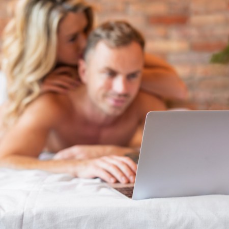 Couple lying in bed and using laptop computer together