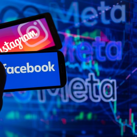Instagram and Facebook logos on a phone in front of the Meta logo.