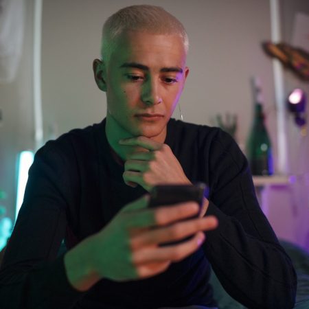 A person with hand on their chin looking at their phone.