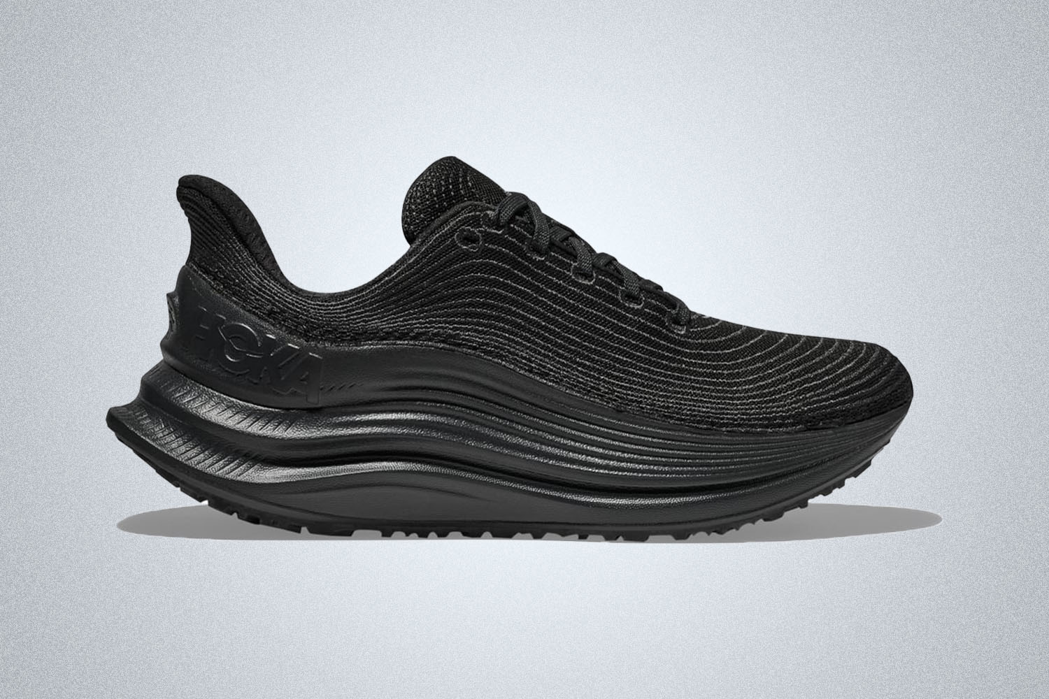 an all black Hoka TC 1 shoe on a grey background