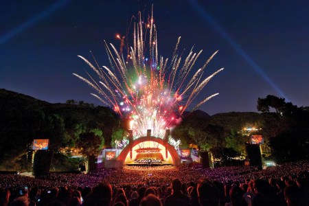 fireworks blasting in the air over a crowd and stage