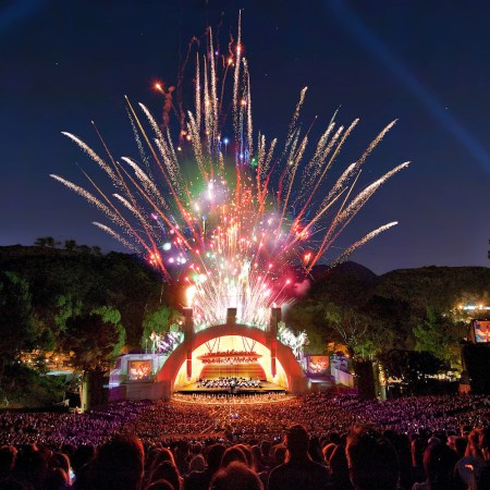 fireworks blasting in the air over a crowd and stage