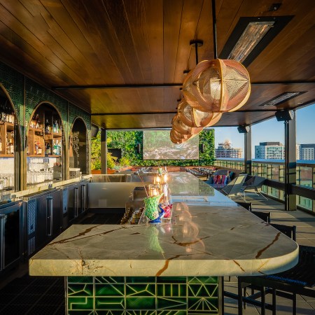 green bar area with seating on rooftop overlooking city skyline