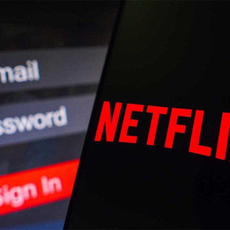 In this photo illustration, the Netflix logo is displayed on a smartphone screen, next to a login screen, with email, password, and sign in.