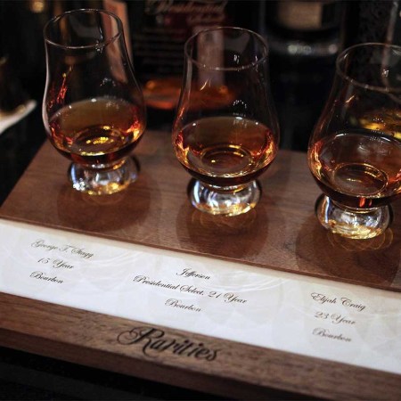 Three pours of rare bourbon on a tasting mat at the NYC bar Rareties. Some bourbons, while high quality, are way too much money to spend on.