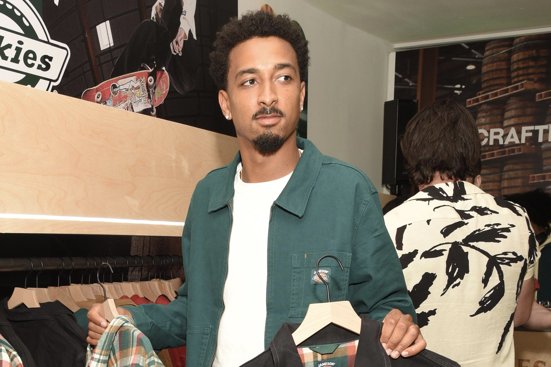 Travis Bennet hold up clothes at an event.