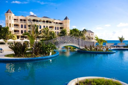 Body of blue water with a bridge and tall building resembling a castle.