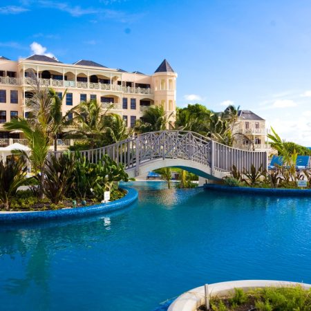 Body of blue water with a bridge and tall building resembling a castle.