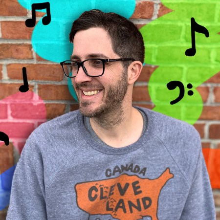 Rob Harvilla posing against a brick wall with musical notes.