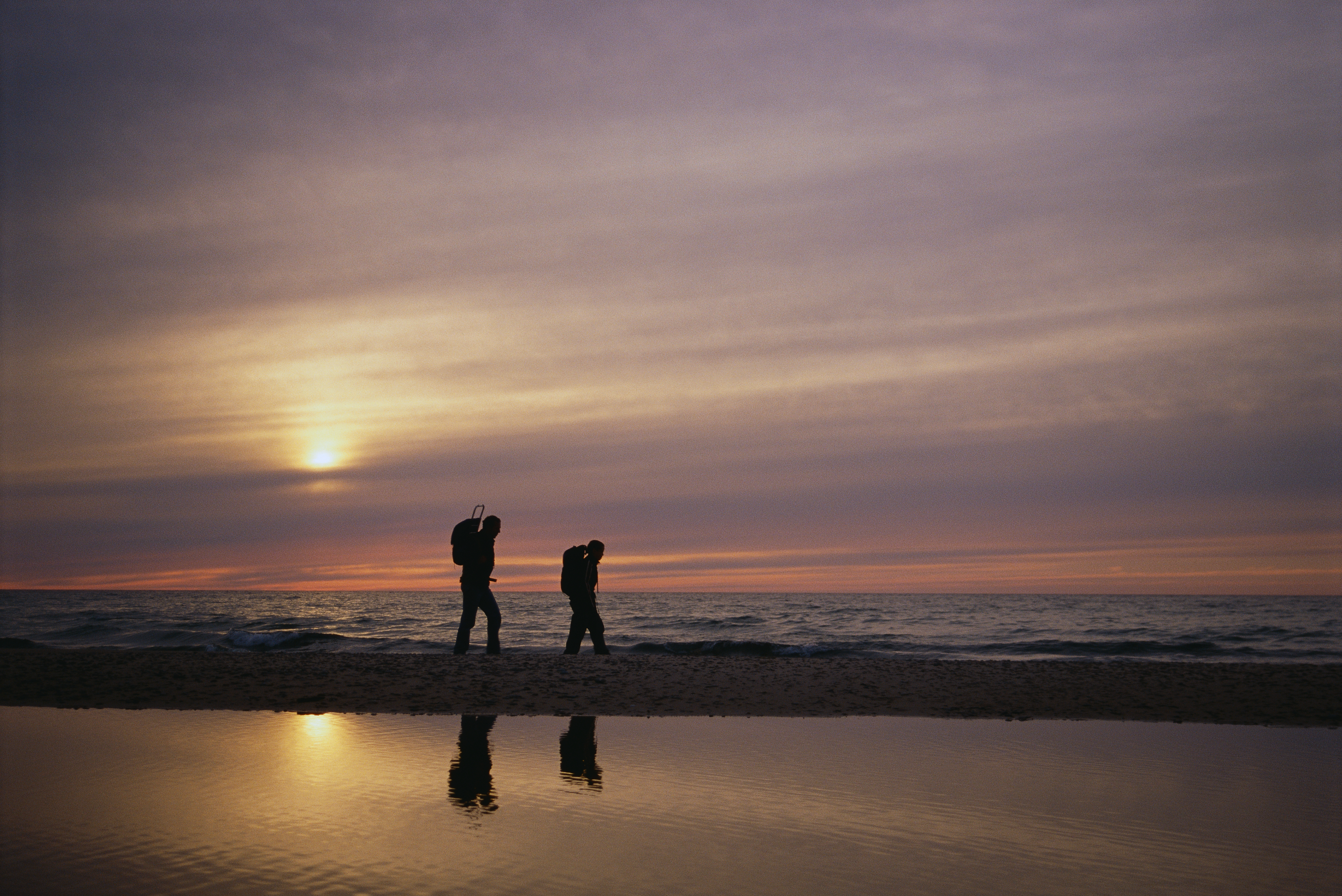 A father and a son walking next to a lake.
