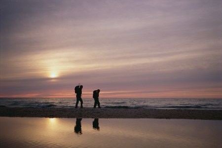 A father and a son walking next to a lake.