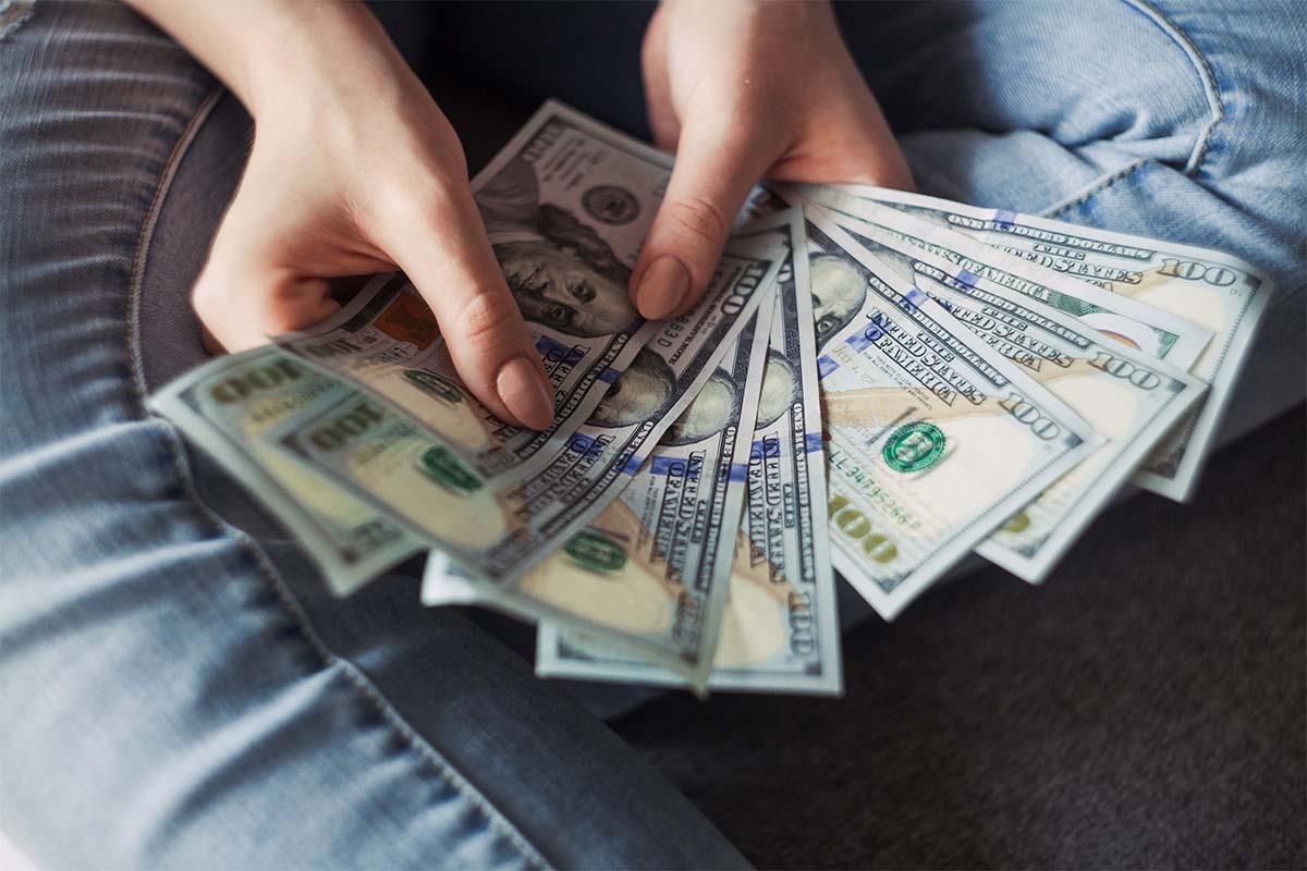 A person displaying dollar bills. A new survey suggests Americans define wealth has having an average of $2.2 million