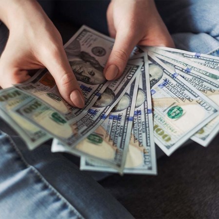 A person displaying dollar bills. A new survey suggests Americans define wealth has having an average of $2.2 million