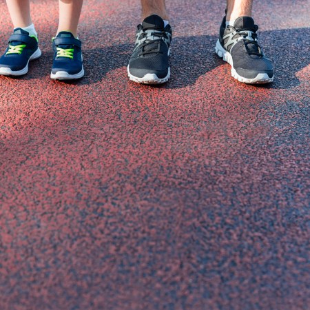 Father and son with big and little sneakers lining up on a track.