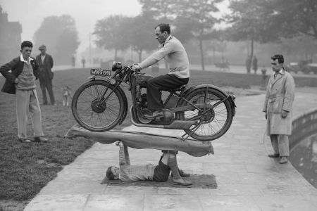 A kid lifting a man on a motorbike in a black-and-white tint.