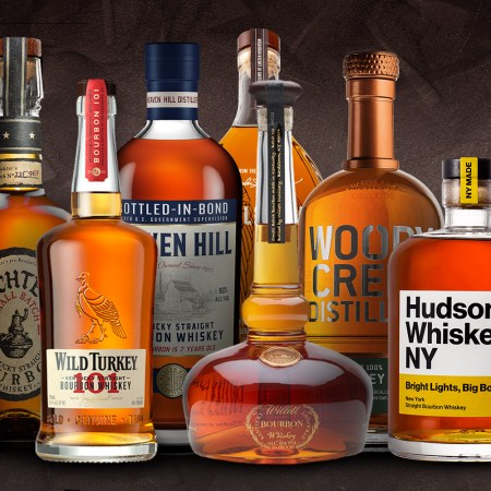 a lineup of bourbon bottles on a textured grey background