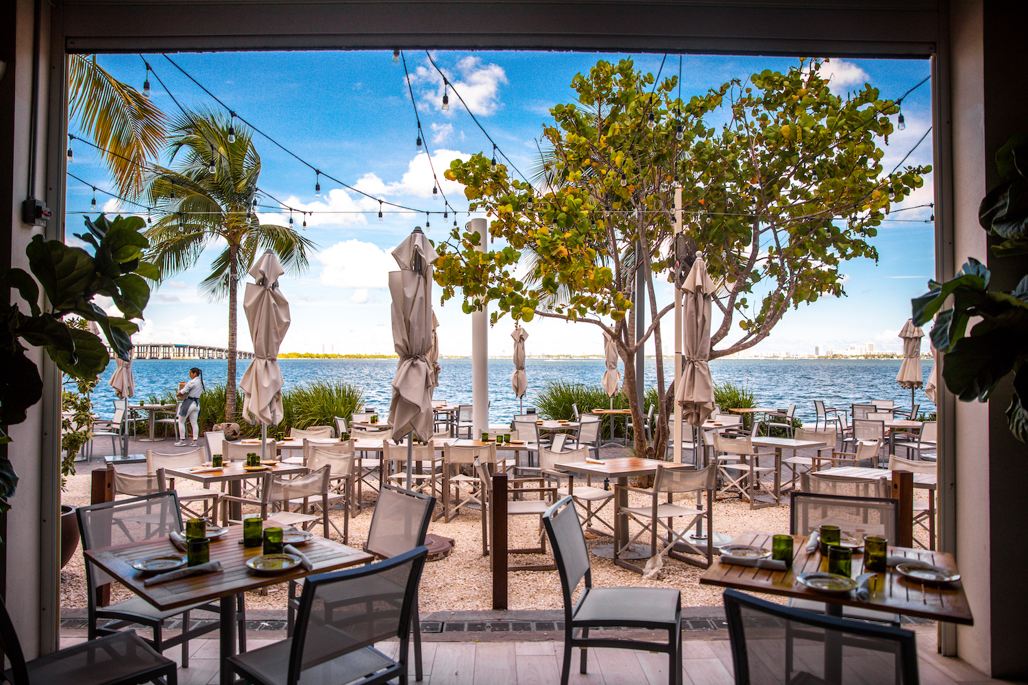 View of tables and chairs at a restaurant in front of the water.