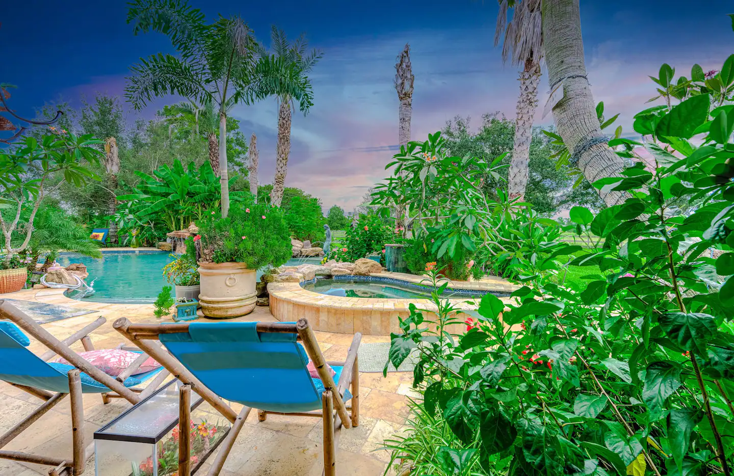 Pool and hot tub surrounded by greenery.
