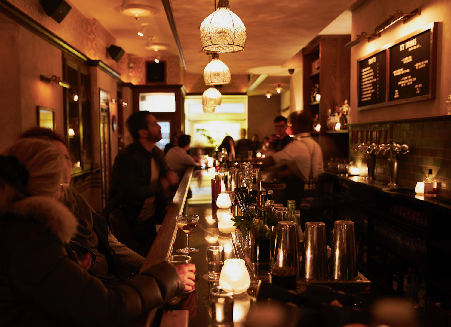 Dimly lit bar with view of bartenders making drinks