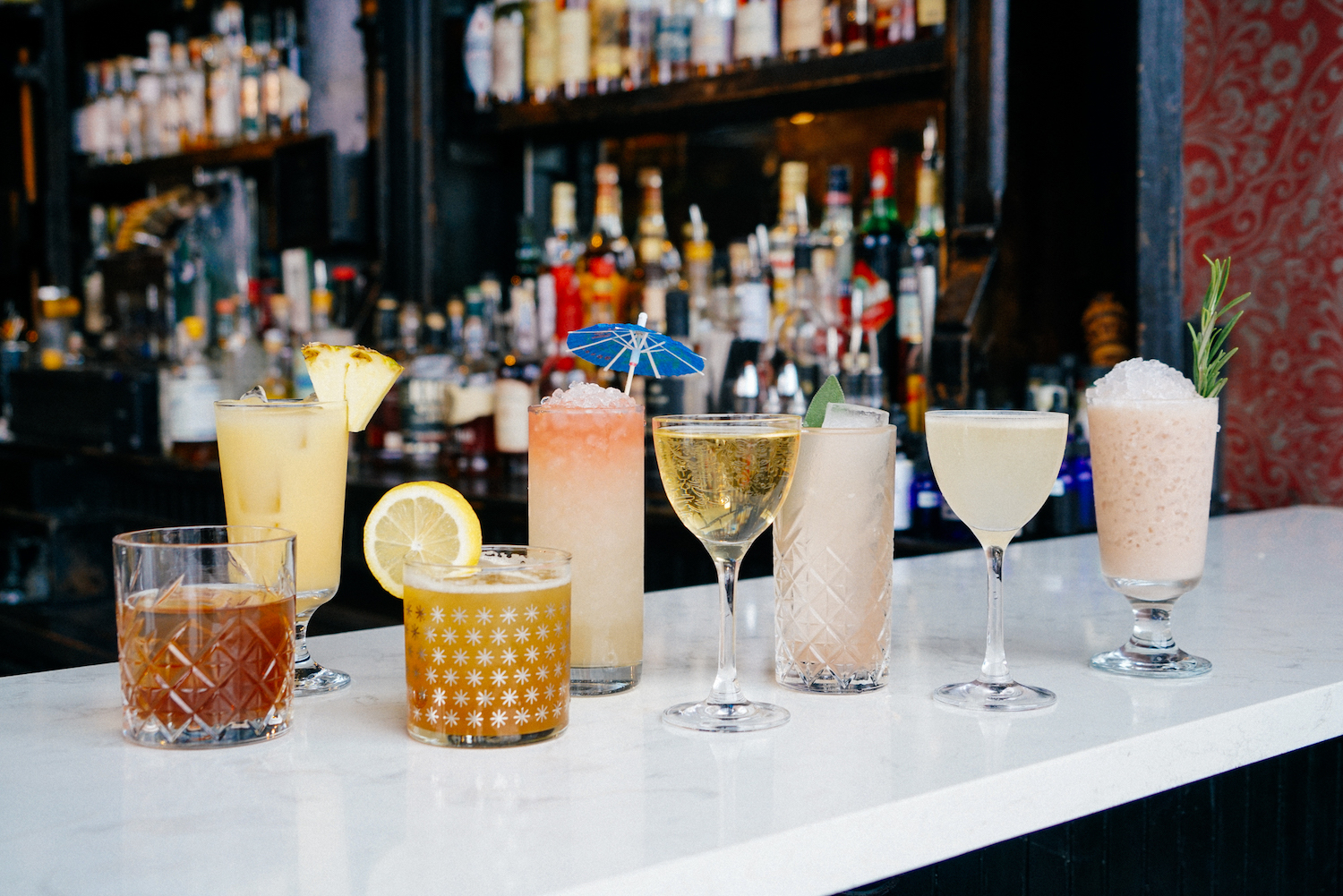 Various cocktails sitting on a bar.