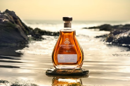 A bottle of Glenglassaugh scotch against a beach background.