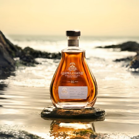 A bottle of Glenglassaugh scotch against a beach background.