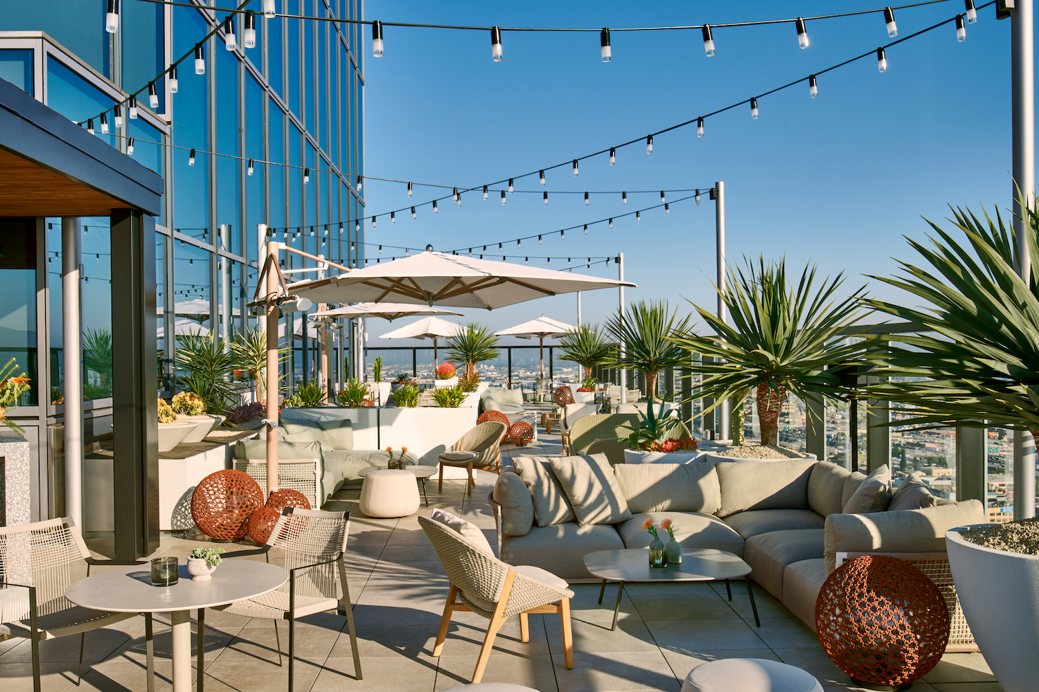 rooftop bar with string lights, couch seats and plants.