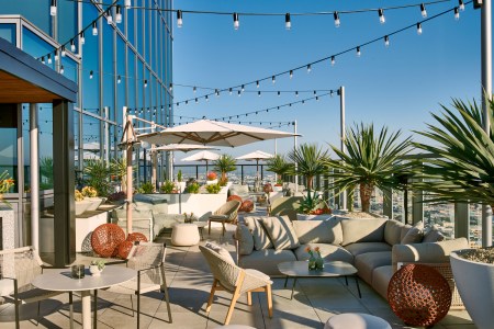 rooftop bar with string lights, couch seats and plants.
