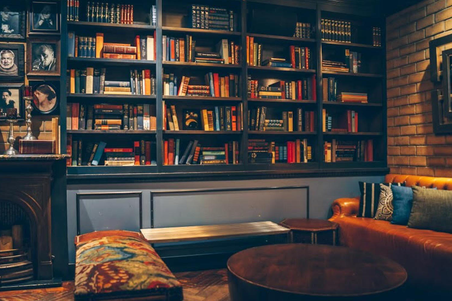 Seating area in front of floor-to-ceiling bookcase and art in frames.