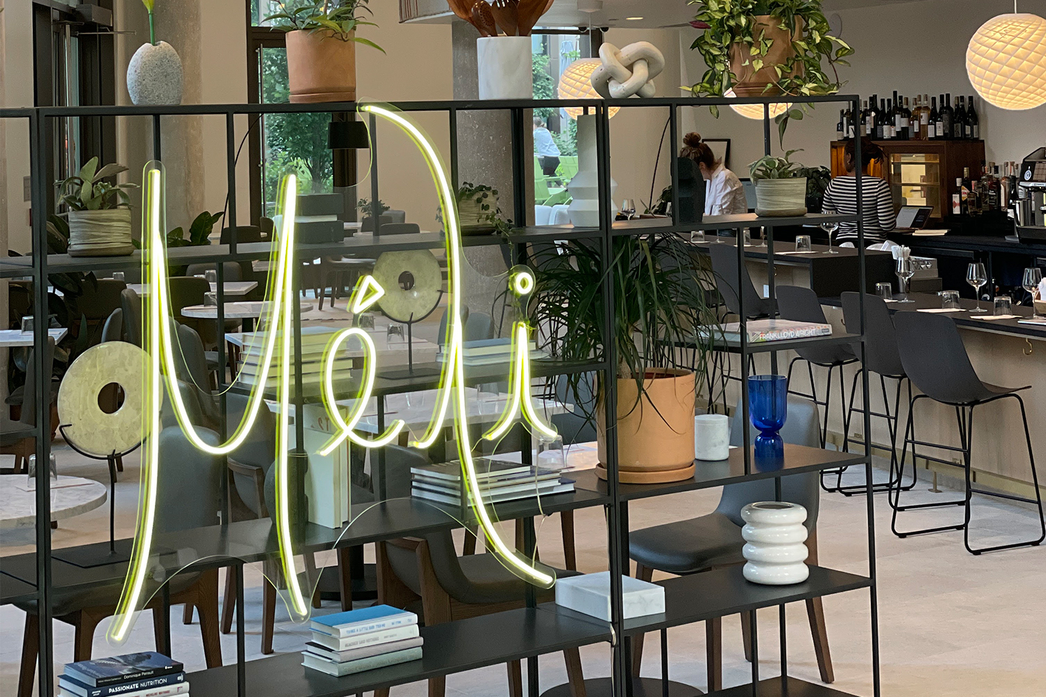 seating area of Méli restaurant and neon green-yellow sign.