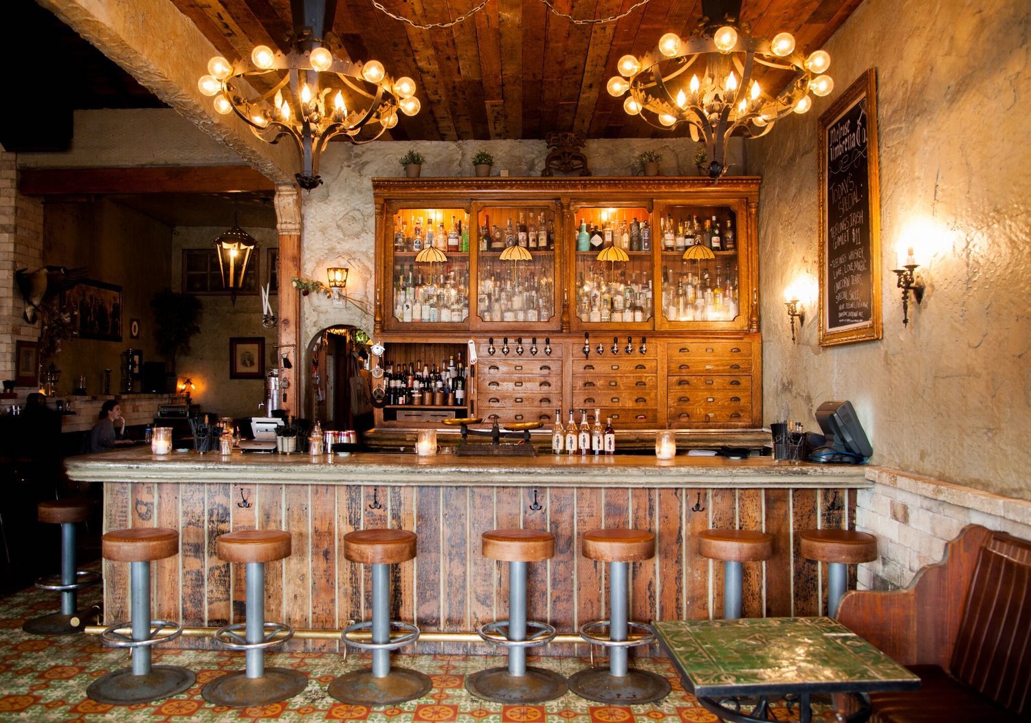 Bar with a woodsy design, brown bar stools and a brown cabinet with bottles.