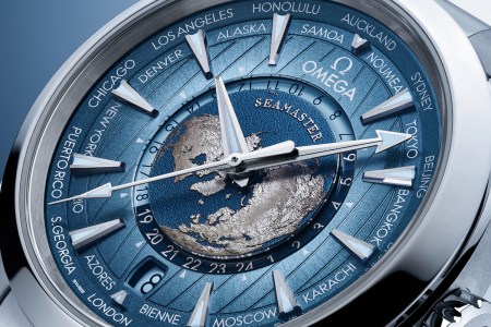 Up-close shot of a watch face that's blue with silver outlines of continents against a darker blue sphere, resembling Earth.