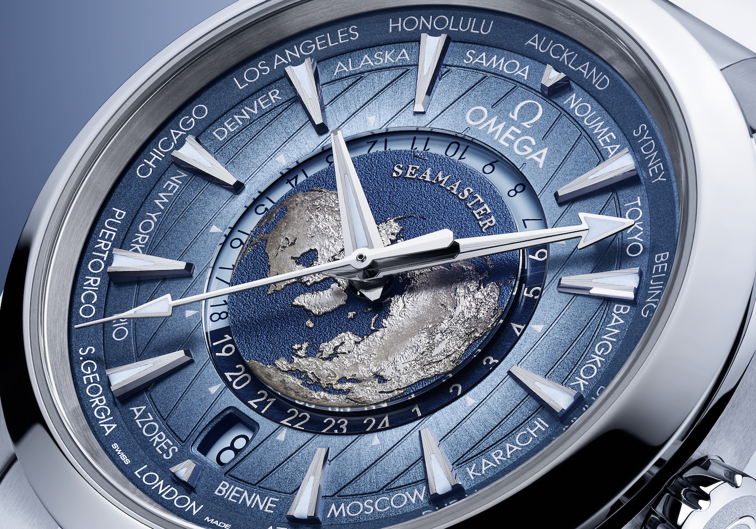 Up-close shot of a watch face that's blue with silver outlines of continents against a darker blue sphere, resembling Earth.