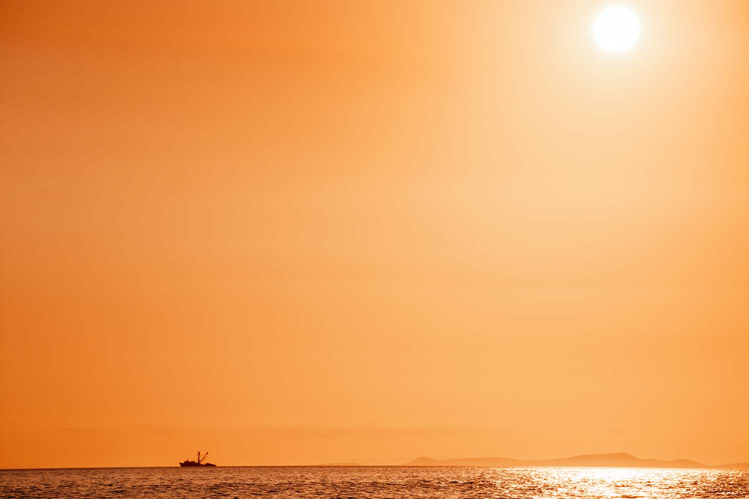 Silhouette of a shrimp boat against a red Baja sunset