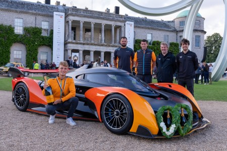 Group of men huddled around winning McLaren.