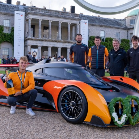 Group of men huddled around winning McLaren.