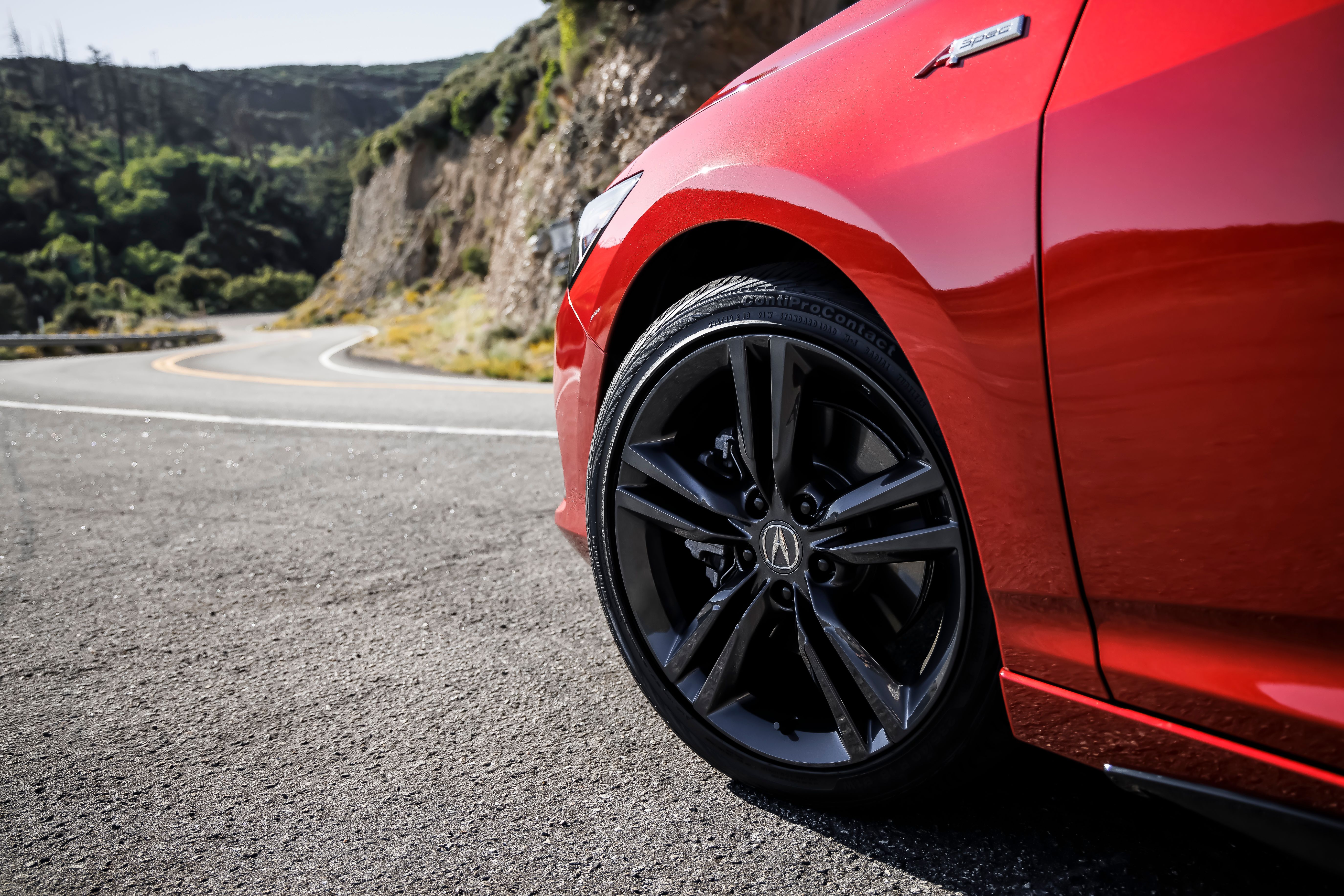The driver's side front wheel area of a red 2023 Acura Integra 6MT