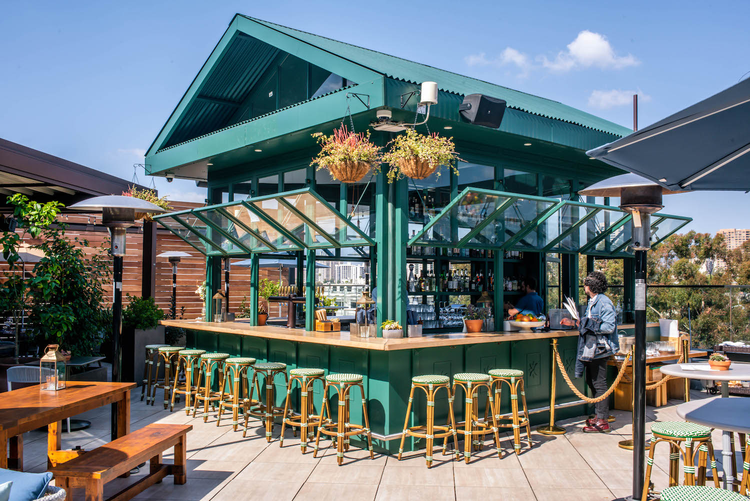 Greenhouse-designed bar on a rooftop with plants.