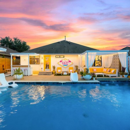 pool underneath a sunset with chairs and a cabana