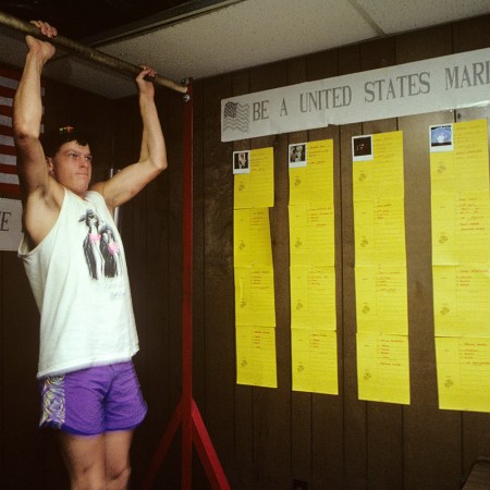 A Marine recruit performing pull-ups in an old-school facility.